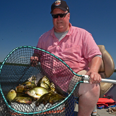 image of fisherman holding net full of slab crappies