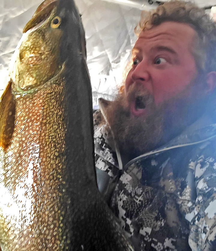 image of Andy Arola holding big Lake Trout caught while ice fishing