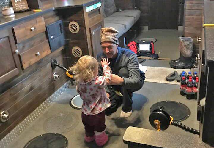 image of father and daughter ice fishing in a sleeper house