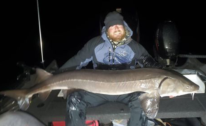 image of Ben Tompkins with monster sturgeon caught on the Rainy River