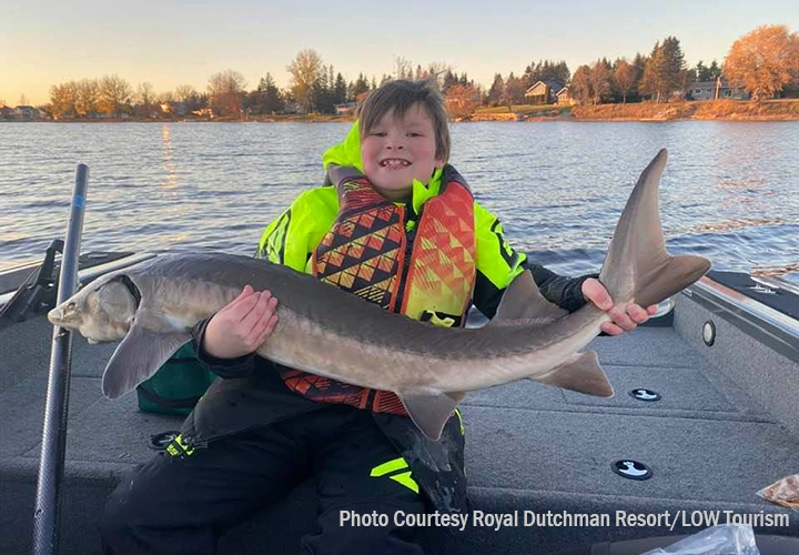 image of kid holding large sturgeon