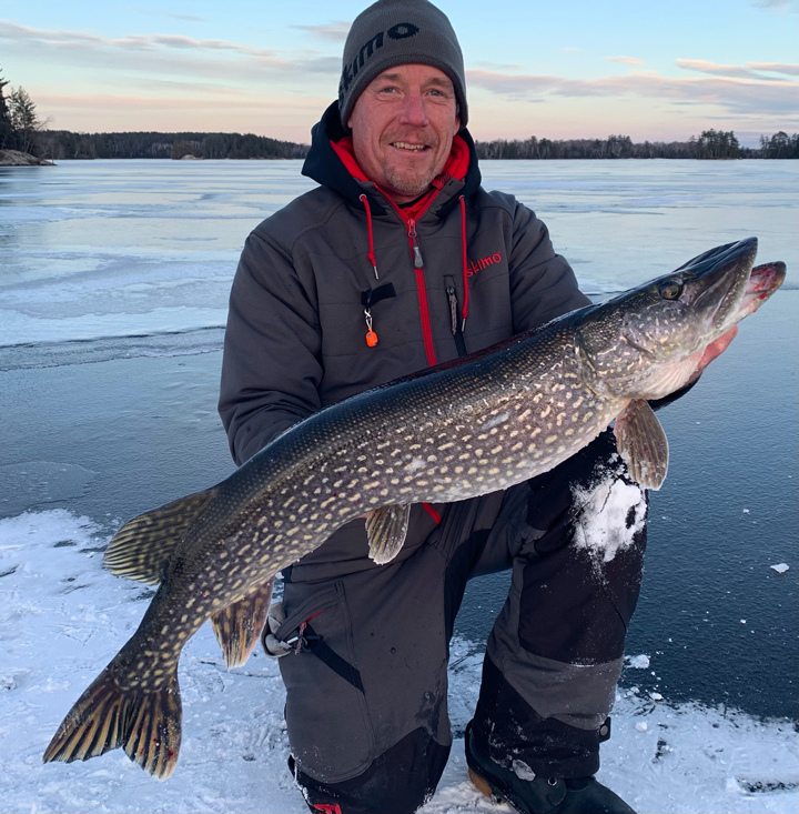 image of ice fisherman holding big northern pike caught in the Ely area