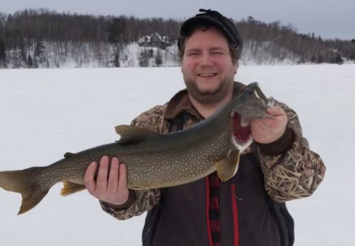 image of ice fisherman holding nice lake trout caught in the grand rapids area