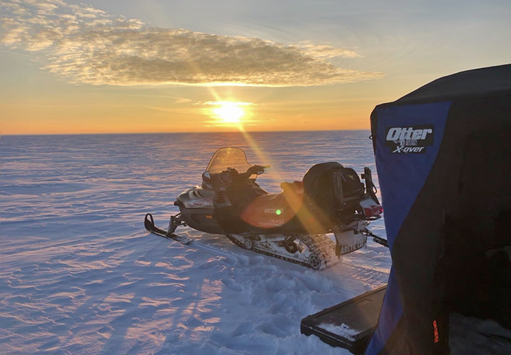 image of snowmobile and portable ice fishing shelter on the ice