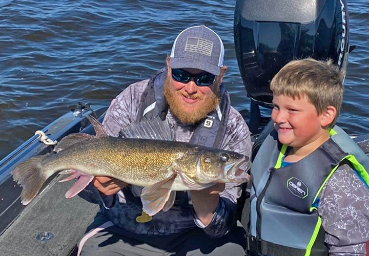 image of fishing guide holding walleye caught by youngster at Sunset Lodge 