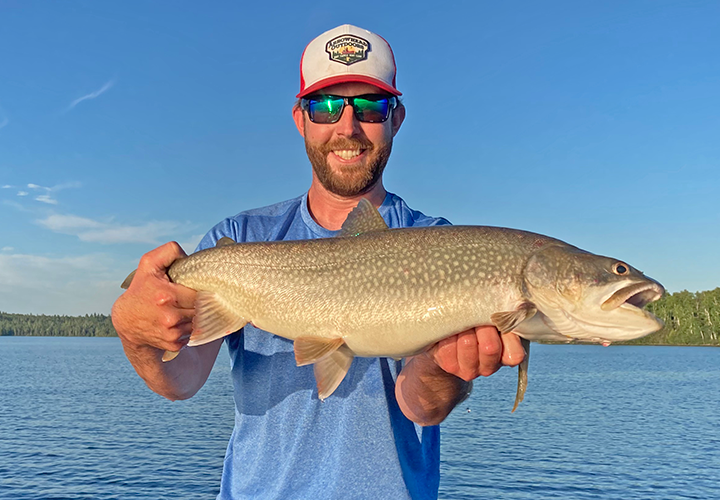 image of fisherman holding big lake trout caught near Ely Minnesota