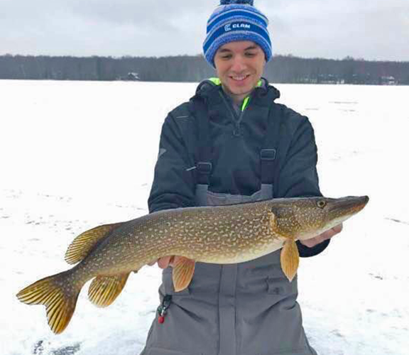 image of young man holding Northern Pike he caught in the Ely MN Region