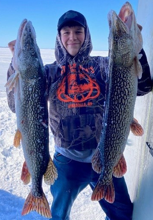 image of ice fisherman holding 2 huge pike caught on Lake of the Woods