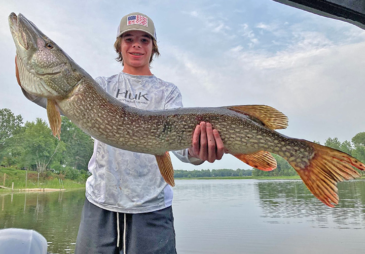 image of young man holding giant northern pike caught on the Rainy River