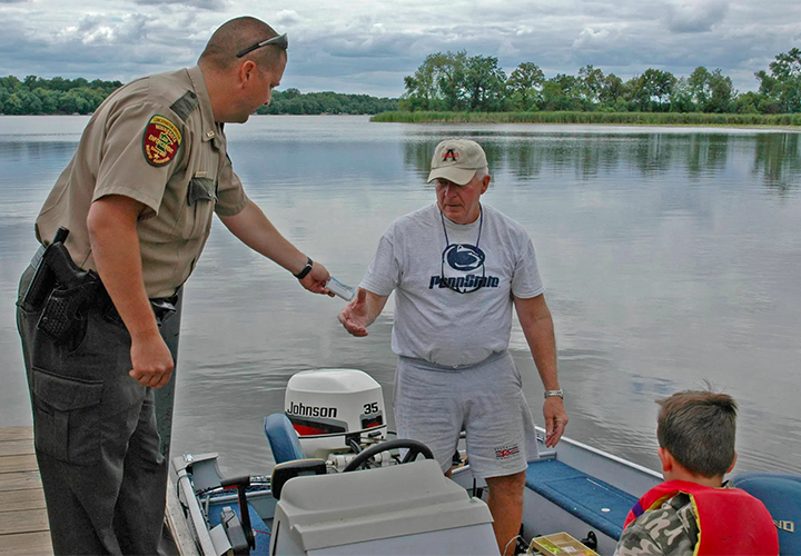 image of Minnesota conservtion officer checking licenses of anglers at the boat dock