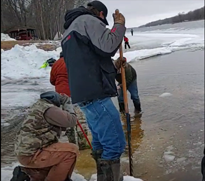 image of men chopping and cutting ice away from the boat ramp at Birchdale on the Rainy 
River