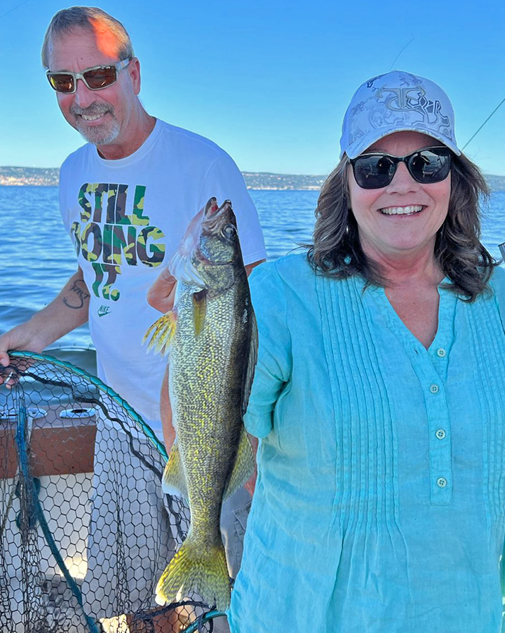 Image of The Hippie Chick and Green Eyes Charter, first mate Greg, showing off walleye caught on charter fishing trip 