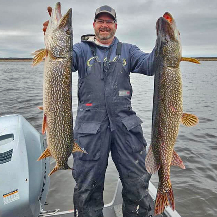 image of angler holding 2 giant pike caught at Zippel Bay