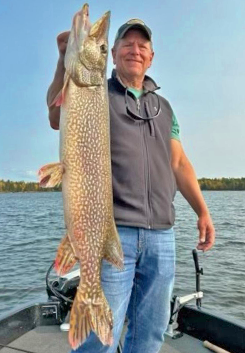 image of fisherman holding huge northern pike he caught on Lake of the Woods