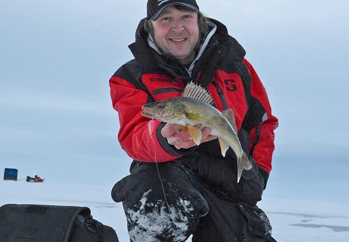 image of ice fisherman holding an upper red lake walleye