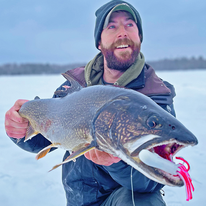 image of ice fisherman holding big lake trout caught near Ely Minnesota