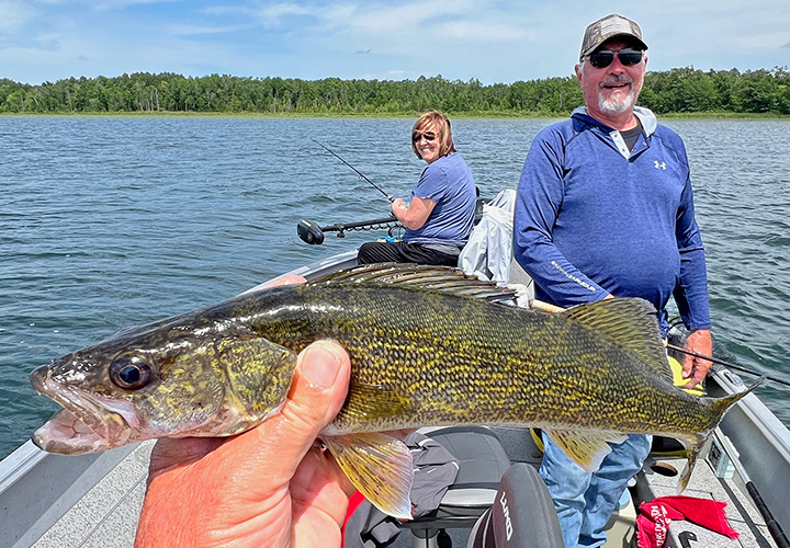 Jeff Sundin shows charter fishing customers Paul and Cindy Guanzinni a walleye caught on the weed edges of a small lake
