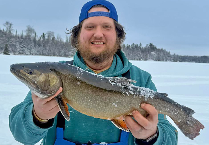 image of happy ice fisherman holding Lake Trout caught in the Ely Minnesota region