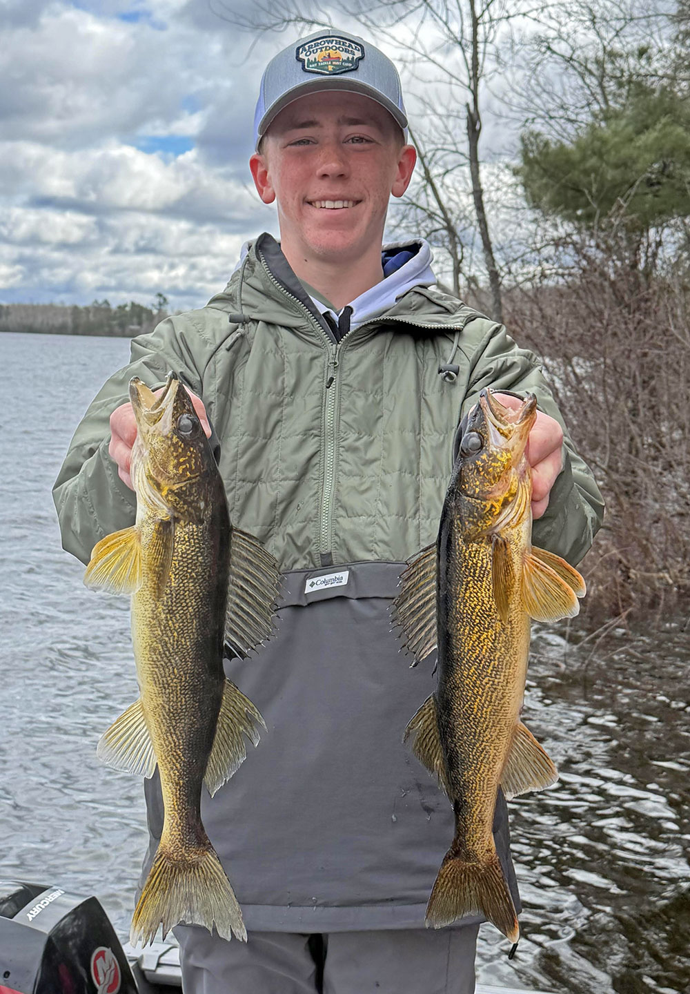 Image of young angler holding 2 nice walleyes he caught in the Ely MN area over the Minnesota fishing opener 