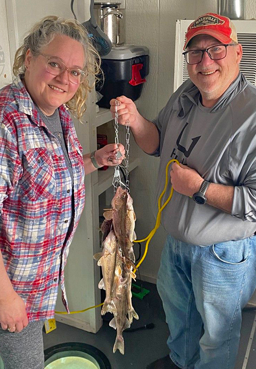 image of couple holding limits of walleye and suager caught on Lake of the Woods while ice fishing
