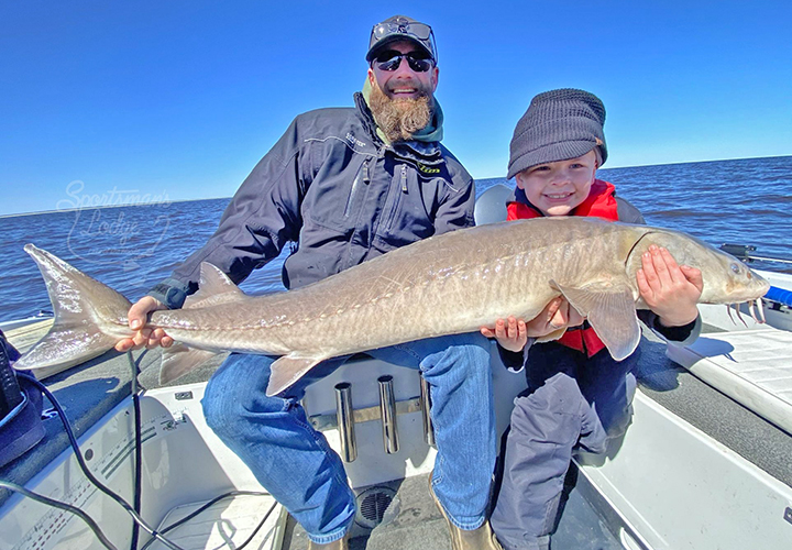 image of father and son fishing team holding huge sturgeon on the Rainy River