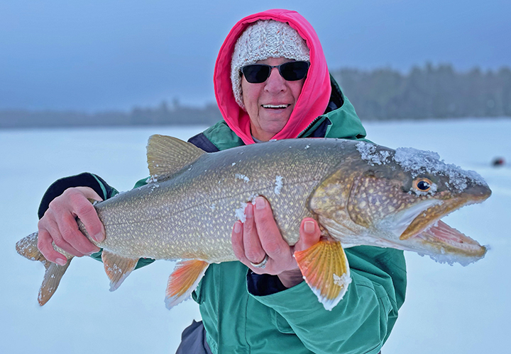 image of ice fisherman holding big Lake Trout caught near Ely Minnesota
