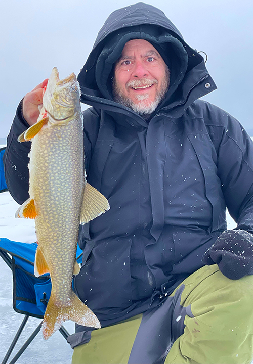 image of ice fisherman holding nice trout caught while ice fishing near ely mn