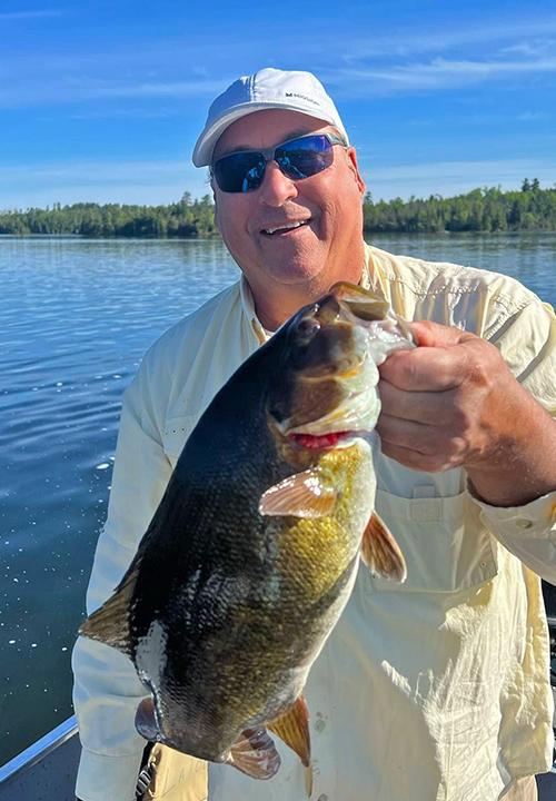 image of fisherman holding huge smallmouth bass he caught in the Ely Minnesota region