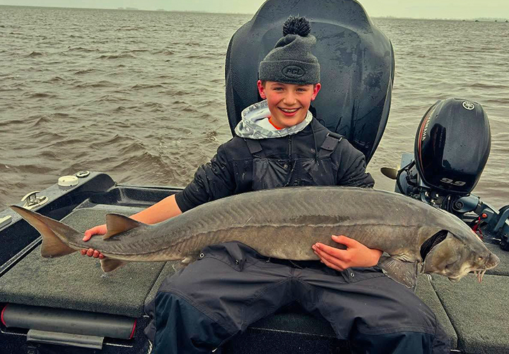 image of young man holding huge sturgeon caught on the Rainy River
